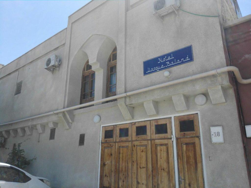 布哈拉Hotel Mosque Baland的一座带木门和蓝色标志的建筑