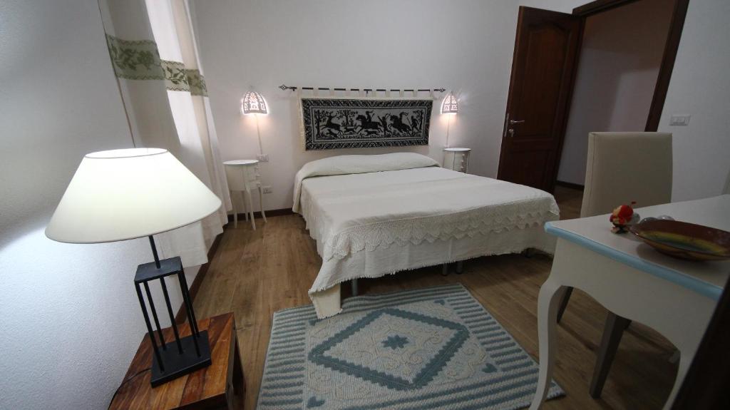 SorgonoAffittacamere Sa Mariola的一间卧室配有一张床、一张桌子和一盏灯
