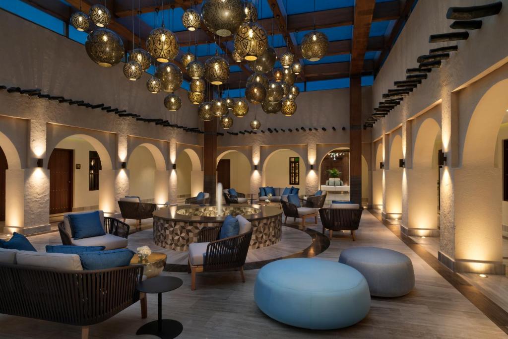 多哈Souq Al Wakra Hotel Qatar By Tivoli的大堂设有桌椅和吊灯。