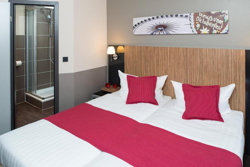 慕尼黑慕尼黑市酒店的一间卧室配有一张带红色枕头的大床
