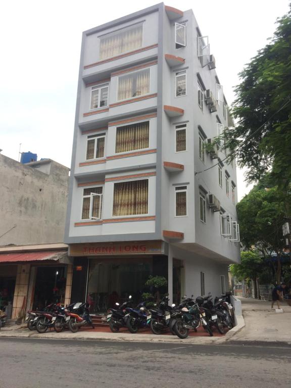 吉婆岛Homestay Thanh Long的一座高大的白色建筑,前面停有摩托车