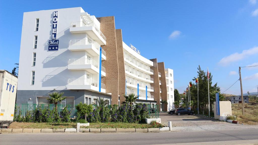 Ghdar DeflaTanger Med Hotel, Conference & Catering的白色的建筑,旁边标有标志