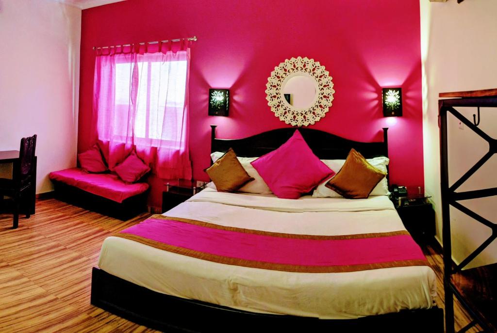 哈里瓦拉卡萨酒店的一间卧室配有一张带粉红色墙壁的大床