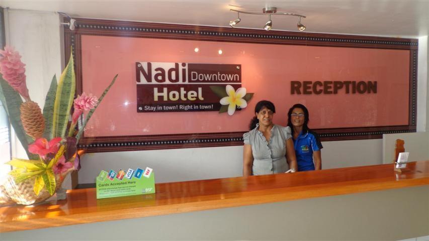 南迪南迪城市中心酒店的两名妇女站在旅馆标志前