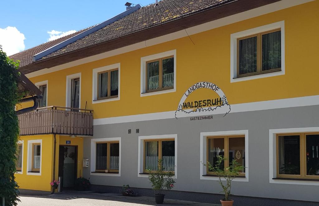 GallspachLandgasthof Waldesruh的黄色和白色的建筑,上面有标志