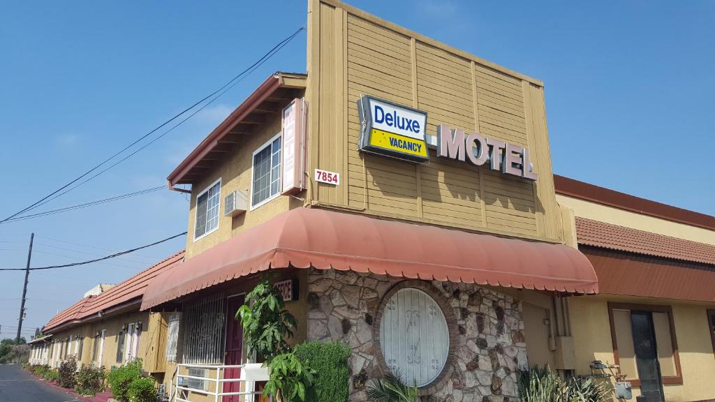 唐尼Deluxe Motel, Los Angeles Area的建筑的一侧有汽车旅馆标志