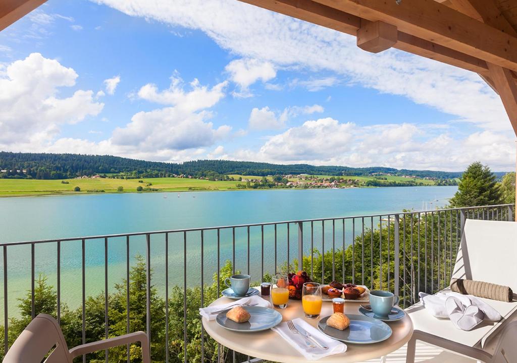马尔比伊松Hotel Spa Les Rives Sauvages的湖景阳台的餐桌