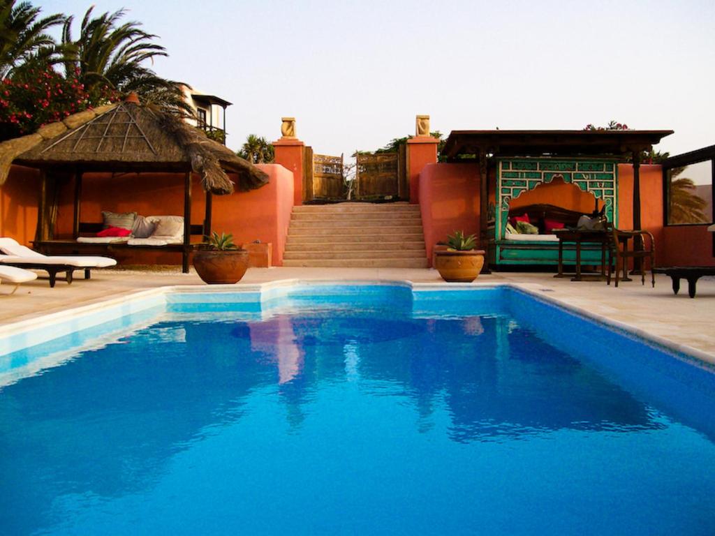 Uga卡萨埃尔莫罗酒店的蓝色游泳池毗邻带凉亭的房子