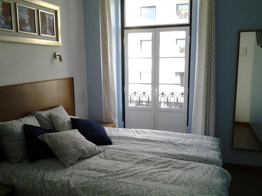 里斯本Baixainn的一间卧室设有一张大床和大窗户
