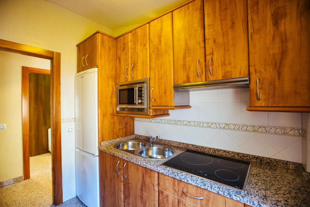 罗德里戈城Apartamentos Arcos的厨房配有木制橱柜、水槽和微波炉
