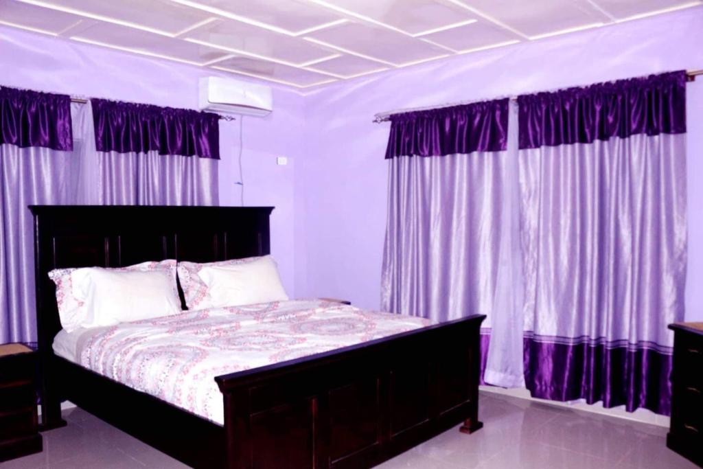 NatrinaMontgomery Brother Estate的一间卧室配有一张大床和紫色窗帘