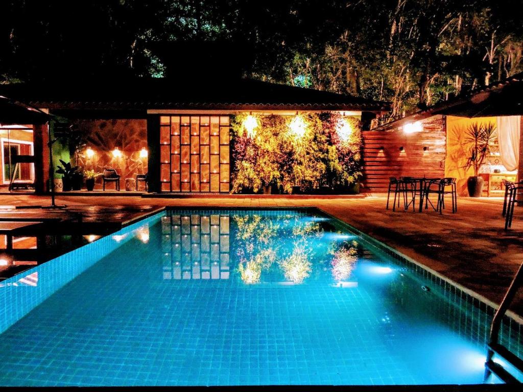 塞拉内格拉Pousada Santa Thereza的夜间在房子前面的游泳池