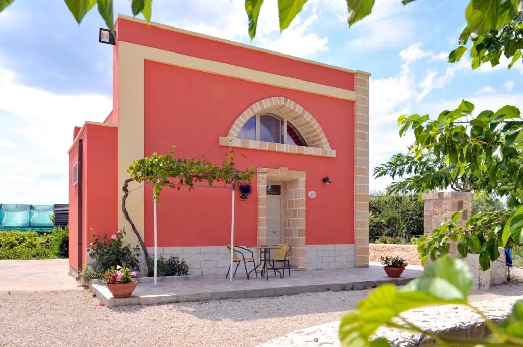 莱韦拉诺Villa Ada Leverano的一座红色的建筑,前面设有桌椅