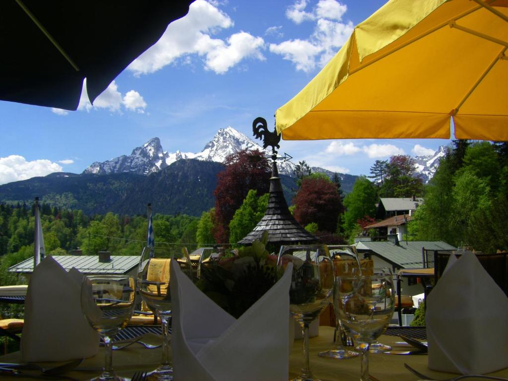 贝希特斯加登科隆普林兹酒店的桌子,上面有眼镜和黄色的伞,还有山