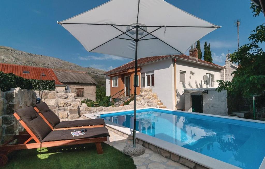 斯林Holiday House with heated pool的游泳池旁的椅子和遮阳伞