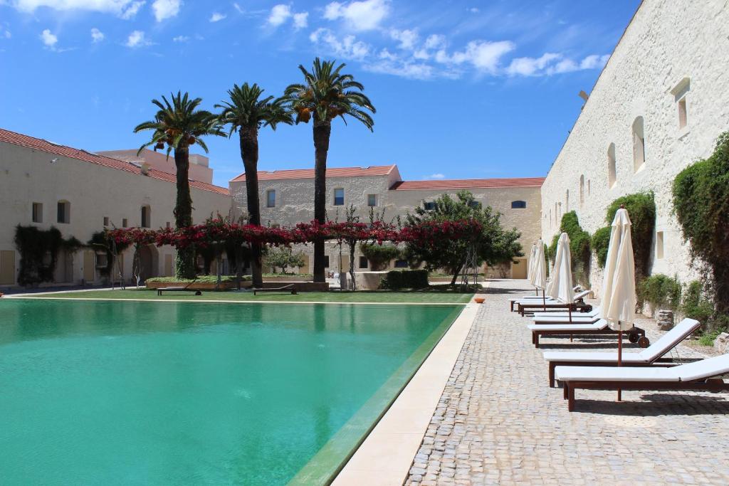 塔维拉Convento das Bernardas AZ的一座游泳池,旁边是椅子和棕榈树