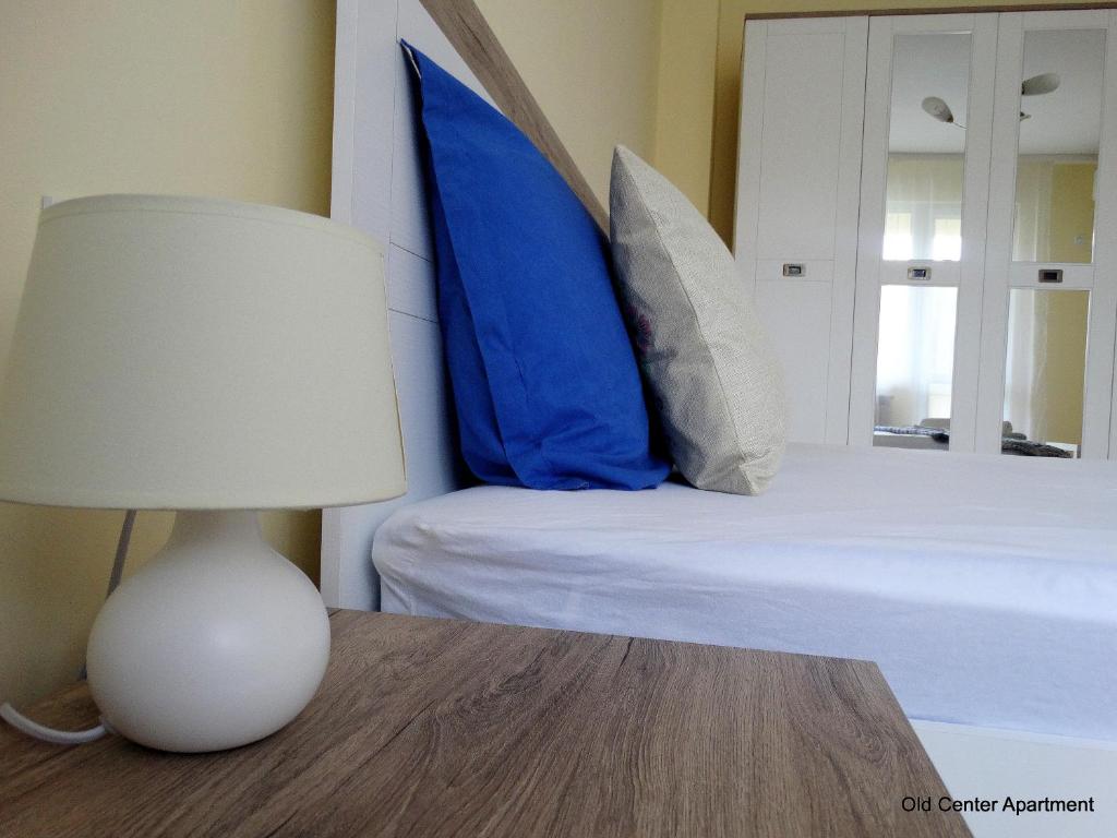 鲁塞Old Center Apartment的一张带蓝色枕头的床和一张带台灯的桌子