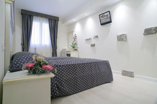帕尔马诺瓦埃道奇酒店的一间卧室配有一张床和一张鲜花桌子