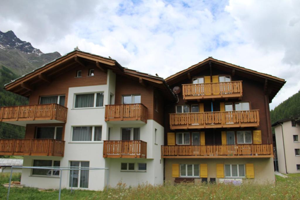 萨斯格伦德Haus Weideli, Dammstrasse 7的公寓大楼设有木制阳台和山脉