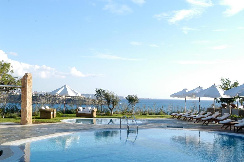 珊瑚湾Thalassa Boutique Hotel & Spa的一个带椅子的游泳池,享有海景