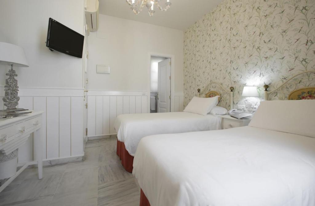 塞维利亚Basic Hotel Puerta de Sevilla的一间酒店客房,设有两张床和电视