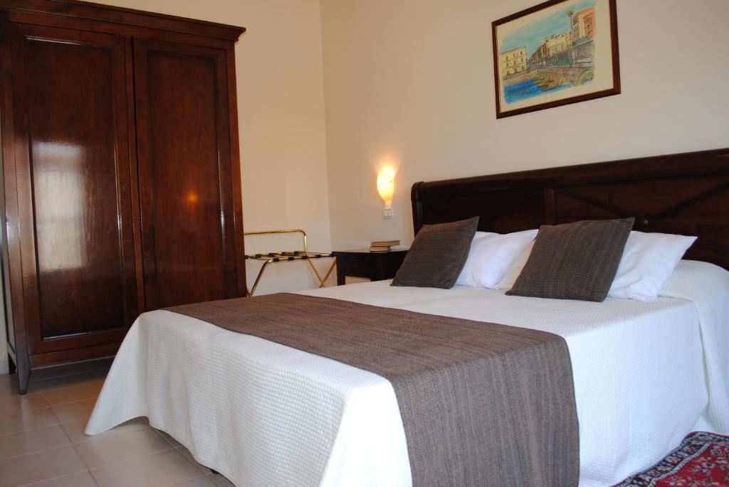 锡拉库扎Hotel Park Siracusa Sicily的一间卧室配有一张带白色床单和木制床头板的床。