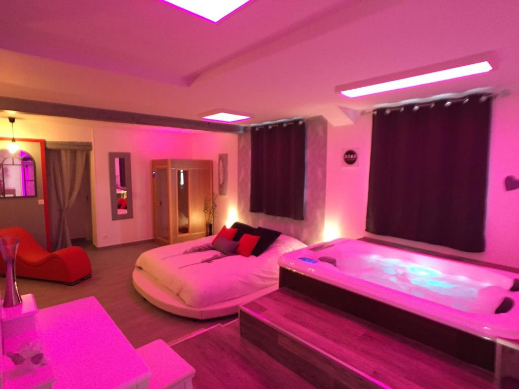 MoisenaySuite Cupidon- Domaine des trois châteaux的一间卧室配有两张床和粉红色的灯光