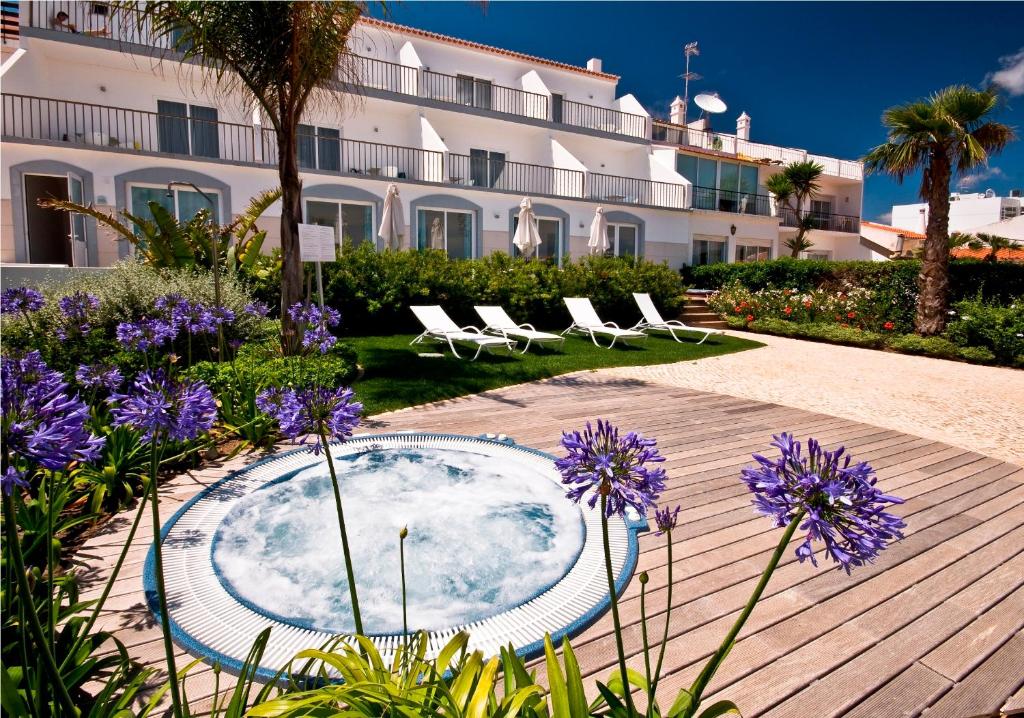 萨格里什马雷塔景观 - 精品住宿加早餐酒店的庭院设有热水浴池、椅子和紫色鲜花