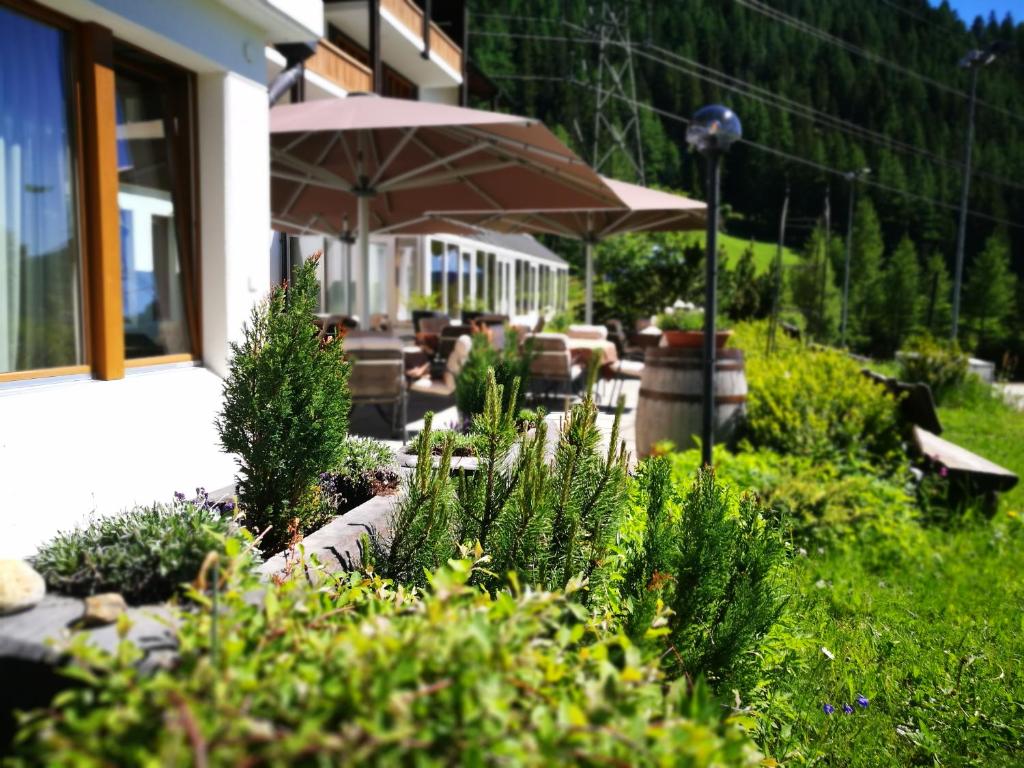 上盖斯特尔恩胡贝图斯酒店的一座种植了植物和遮阳伞的花园,一座建筑