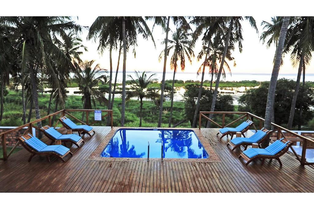 伊尼扬巴内Vertigo Lodge de Estaurio的一个带椅子的甲板和一个棕榈树游泳池
