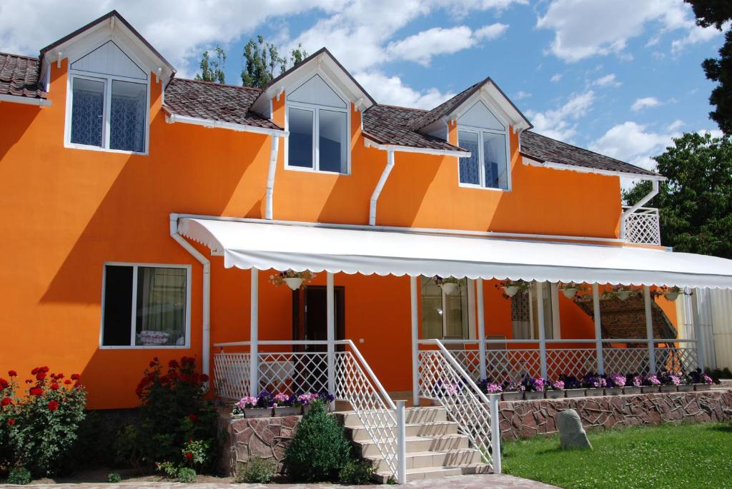 乔尔蓬阿塔Osobyi Guest house的白色遮阳篷的橙色房子