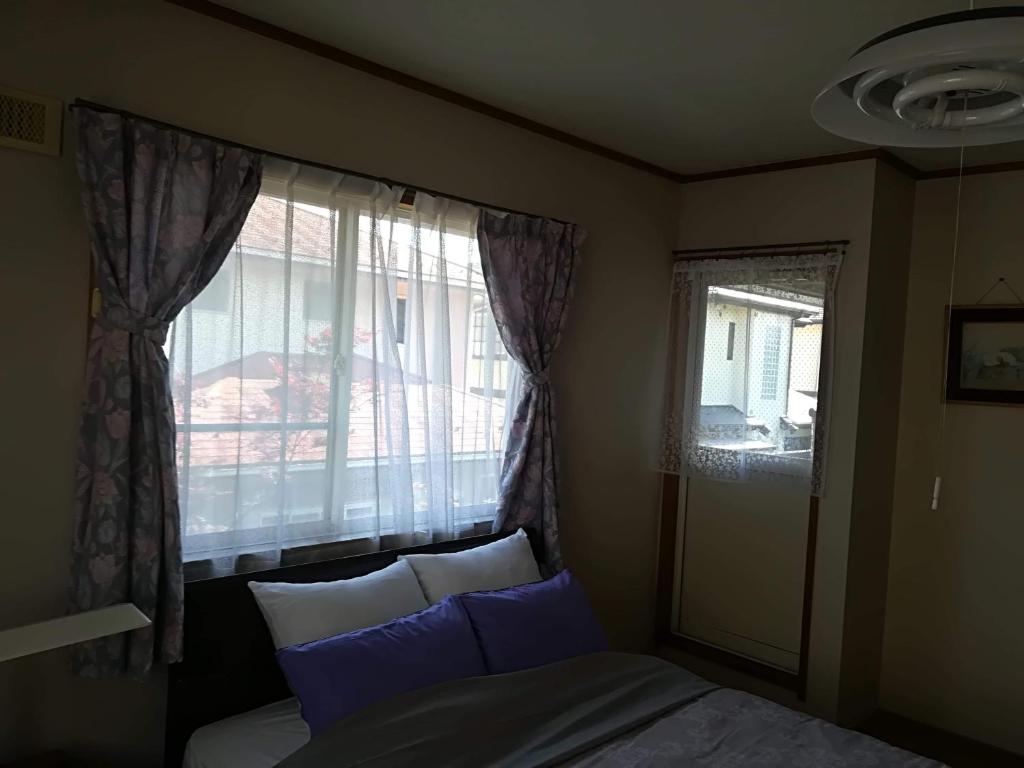 仙台Jukichi Owada Residence的一间卧室配有床和带蓝色枕头的窗户。