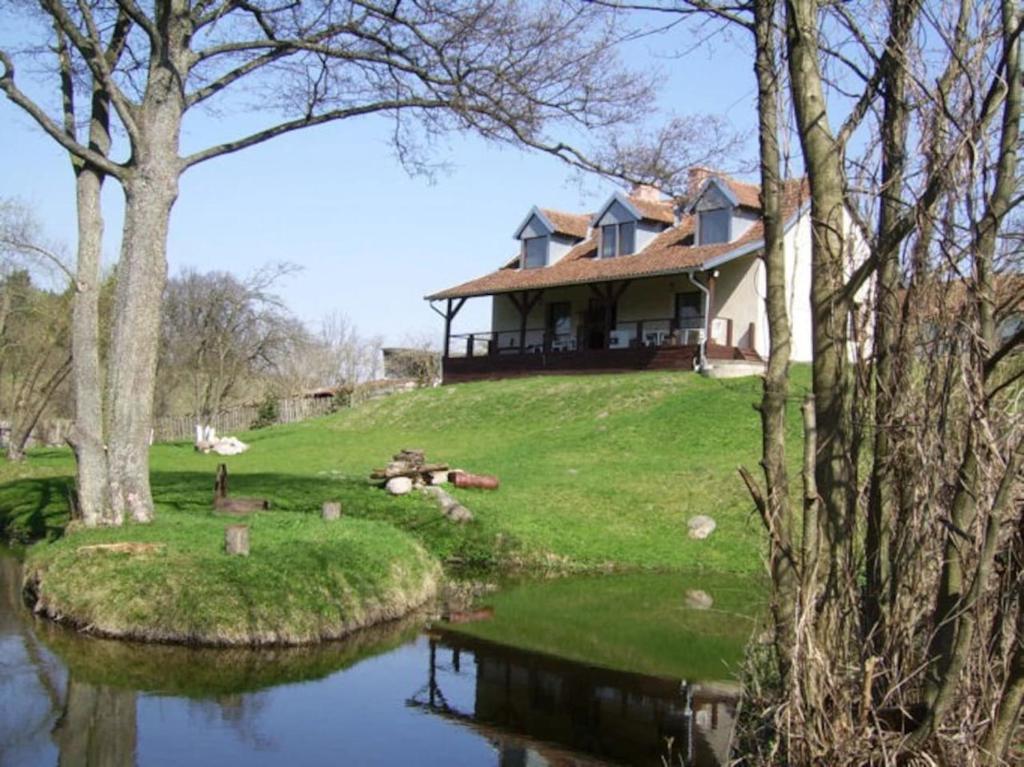 PilecChalupa Dejnowo的坐在河边小山顶上的房子