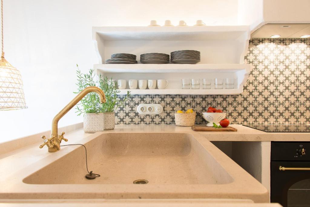 休达德亚Ses Voltes Sant Antoni的厨房里的一个水槽,架子上放有盘子