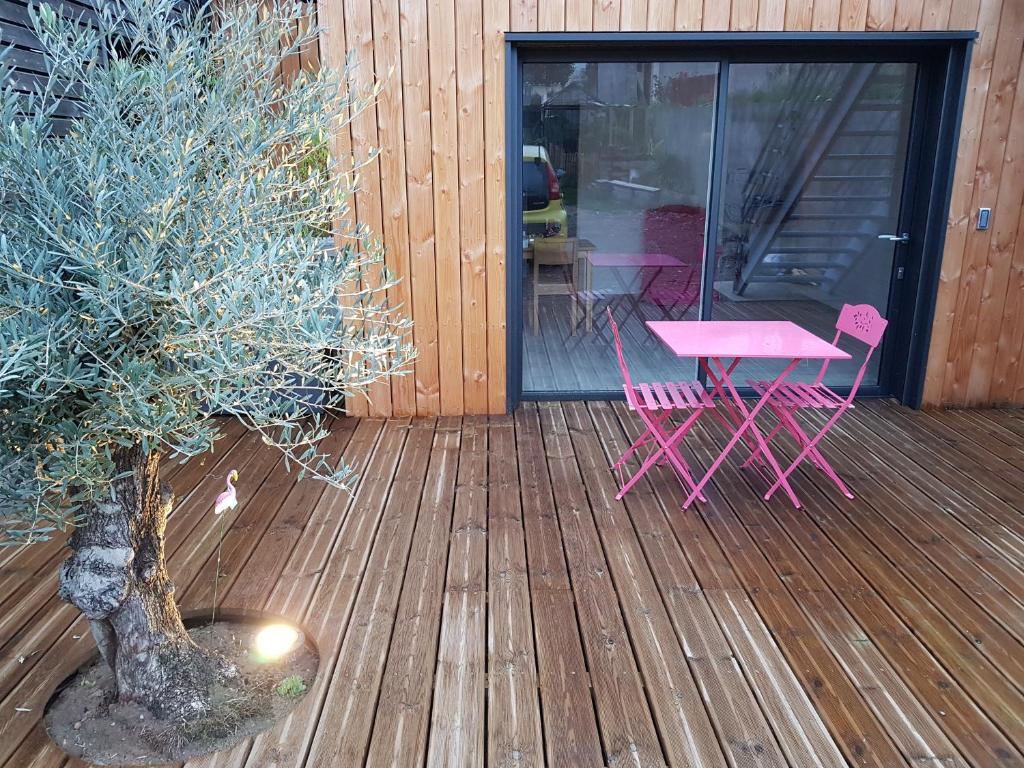 昂热Angers Green Lodge的木甲板上设有粉红色的桌子和一棵树