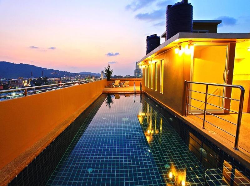 芭东海滩88酒店的一座游泳池,位于一座带灯光的建筑的一侧