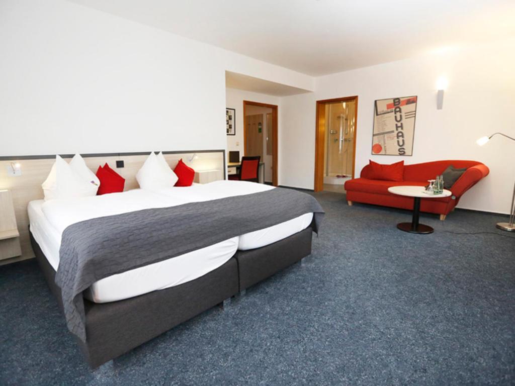 德绍Hotel 7 Säulen GmbH的酒店客房设有一张大床和一张红色沙发。