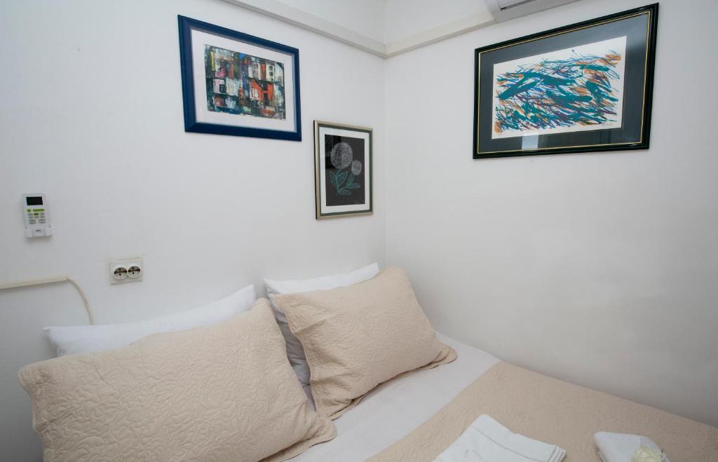 斯普利特Sweet Room Old Town Split的白色的房间,设有一张床,墙上有三张照片
