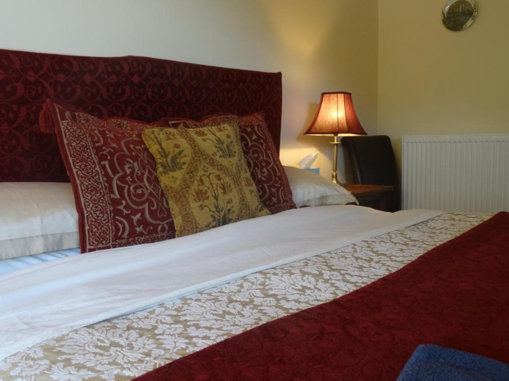 毕晓普斯堡Middle Woodbatch B&B的一张带红白色枕头和灯的床