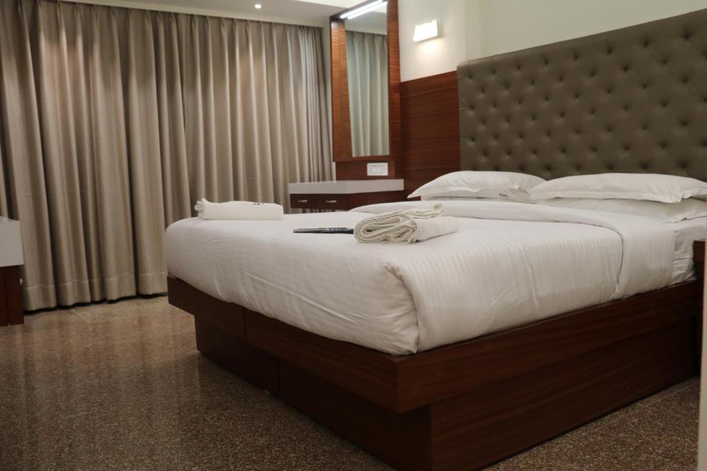 孟买米兰国际大酒店的一间卧室配有一张带白色床单的大床