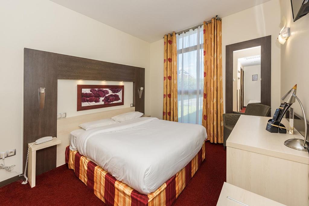 博韦Hostellerie Saint Vincent Beauvais Aeroport的配有一张床和一张书桌的酒店客房