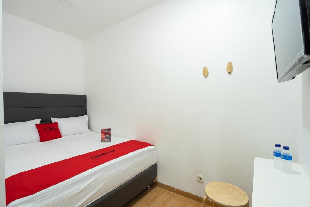 雅加达RedDoorz Plus @ Danau Sunter Utara的一间卧室配有一张带红色毯子的床