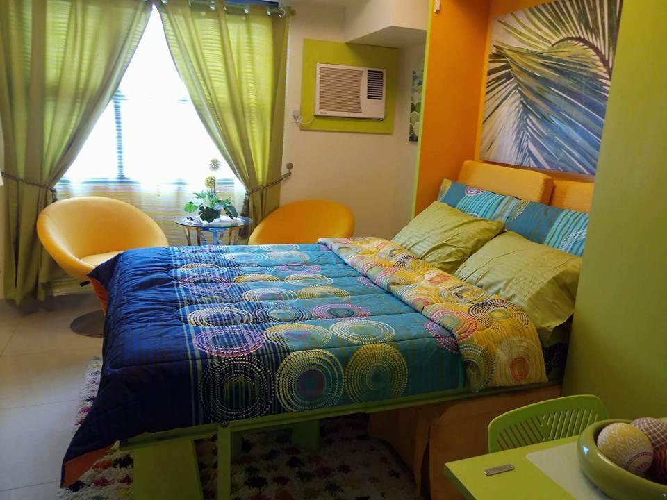 宿务Nica's Place Property Management Services at Horizons 101 Condominium的一间卧室配有一张带五颜六色被子的床