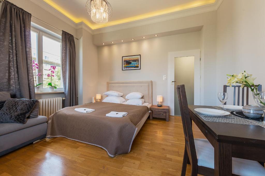华沙P&O Apartments Andersa INTRACO的一间卧室配有一张床、一张桌子和一张沙发