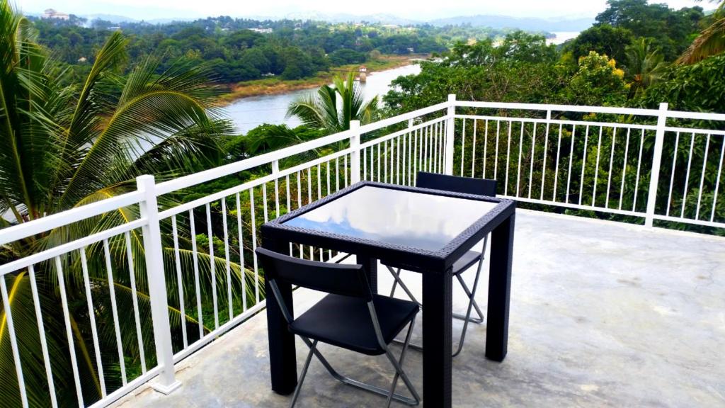 康提Mahaweli View Inn的俯瞰河流的阳台配有一张黑桌椅