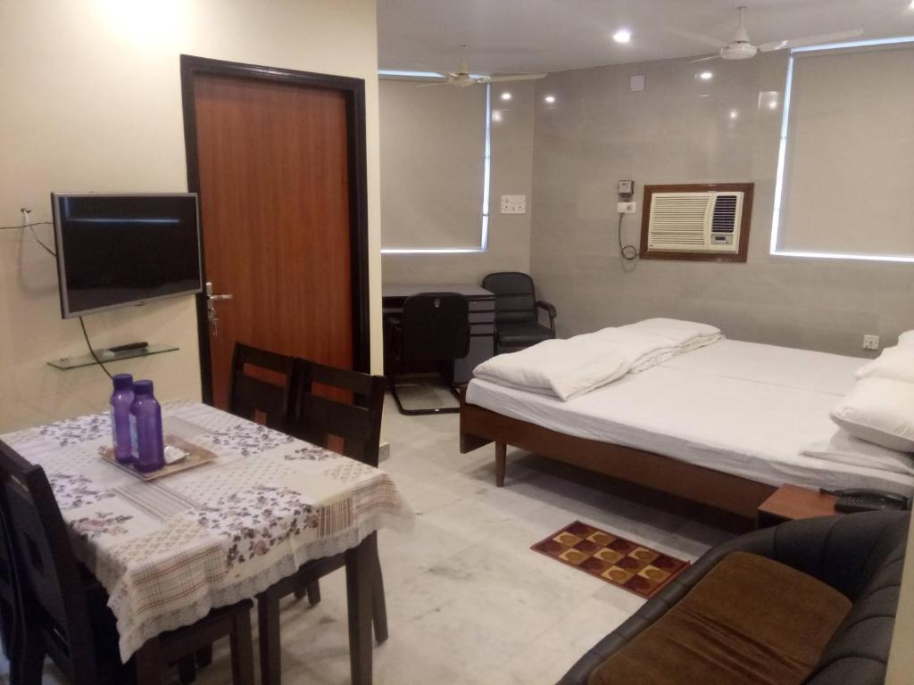 加尔各答Service Apartments, Park Street, Calcutta的客房设有两张床、一张桌子和一台电视机。