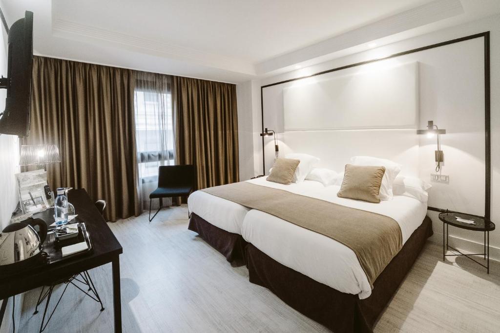 毕尔巴鄂阿万多酒店的酒店客房设有一张大床和一张书桌。