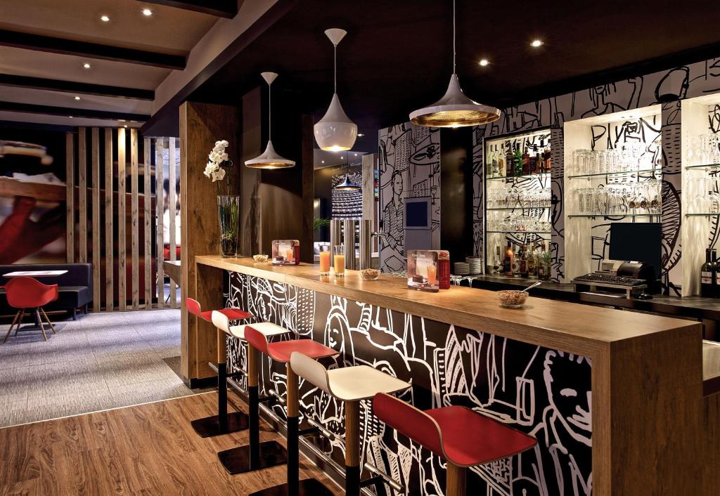 不莱梅布莱梅中心宜必思酒店的餐厅设有红色椅子和酒吧
