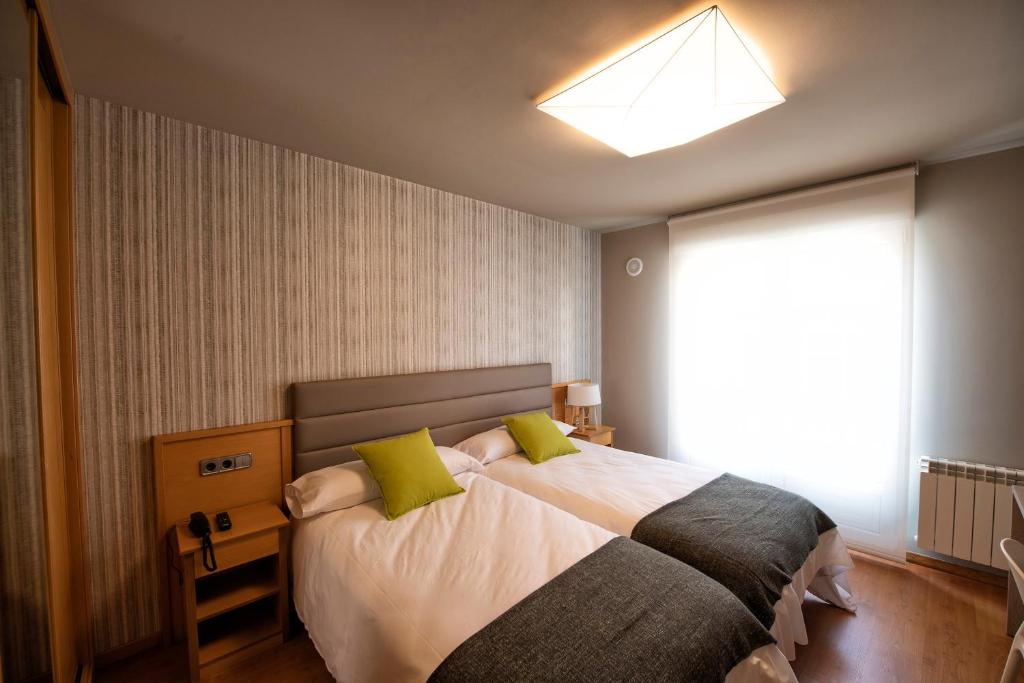 拉赫Hotel VIDA Mar de Laxe的一间卧室配有一张带绿色枕头的大床
