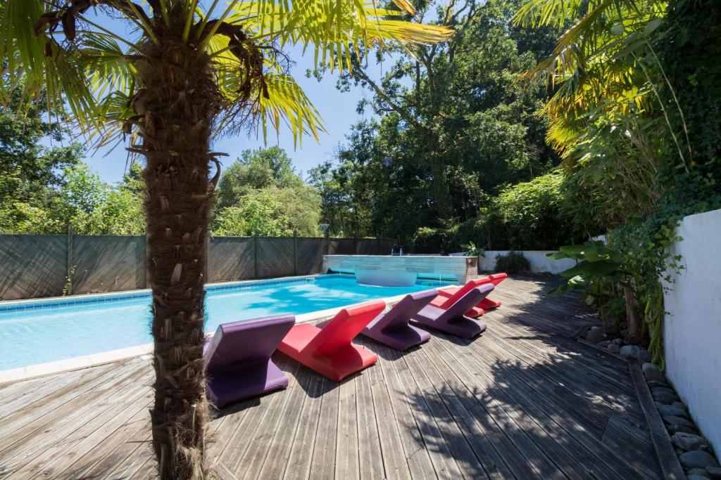 拉巴斯蒂德克莱朗斯伊杜克丘陵酒店的棕榈树旁的游泳池,配有红色和紫色的躺椅